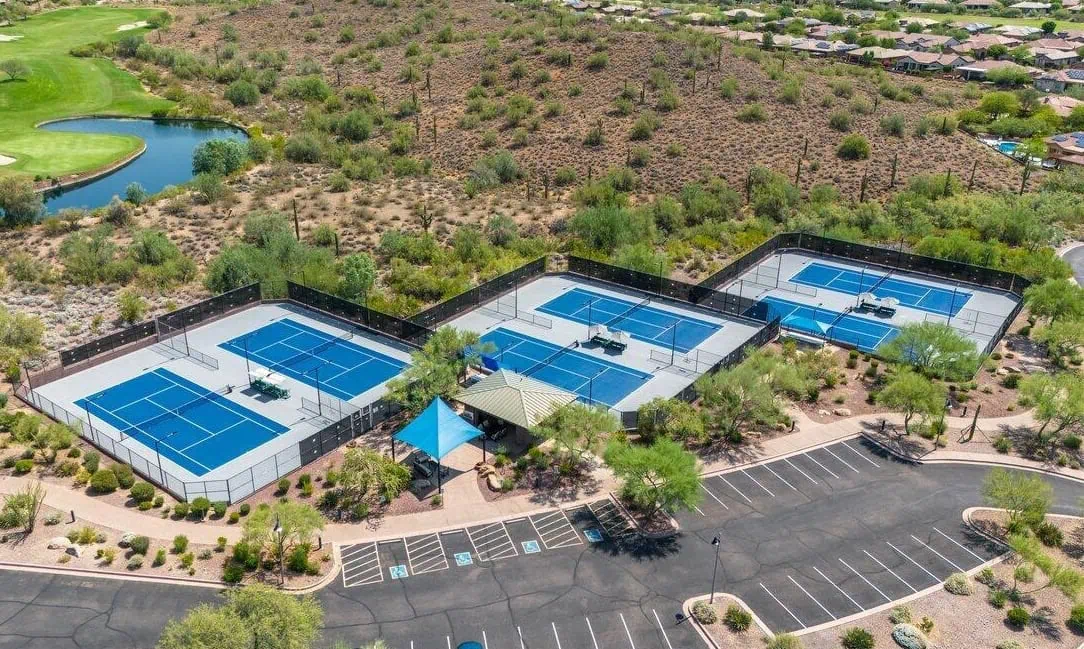 A baseball field in Arizona featuring a close-up view of the home plate area with distinct white lines marking the batter's box and the foul lines. The grassy infield and pitcher's mound are visibly maintained, showing a clear, sunny day perfect for artificial grass installations.
